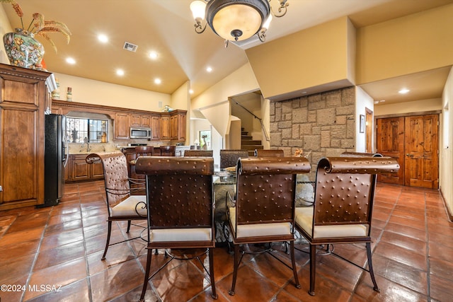 dining area with sink and high vaulted ceiling