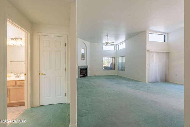 unfurnished living room featuring ceiling fan, sink, and light colored carpet