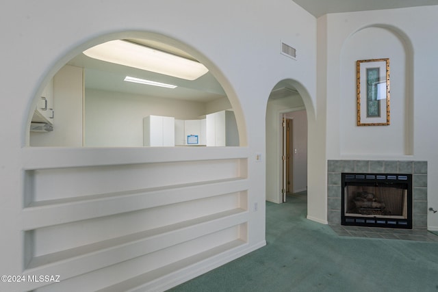 unfurnished living room with dark colored carpet and a tiled fireplace