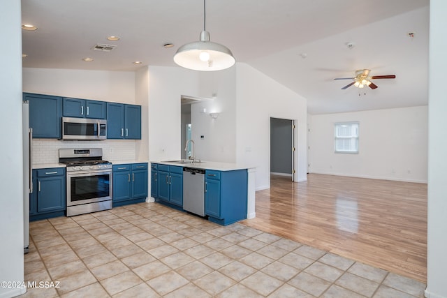 kitchen featuring pendant lighting, sink, blue cabinetry, kitchen peninsula, and stainless steel appliances