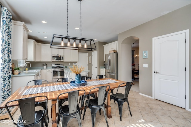 kitchen featuring white cabinetry, decorative light fixtures, stainless steel appliances, and light tile patterned floors