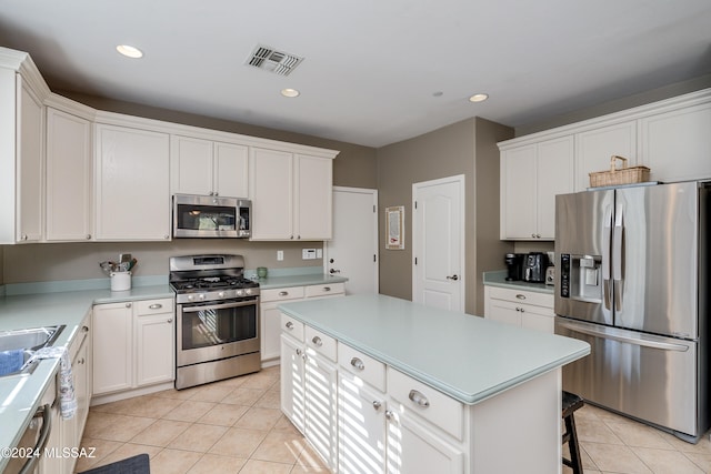 kitchen with appliances with stainless steel finishes, a kitchen bar, a center island, white cabinets, and light tile patterned floors