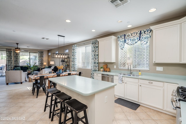 kitchen featuring appliances with stainless steel finishes, sink, a kitchen island, white cabinetry, and pendant lighting