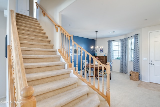 stairs with carpet floors and an inviting chandelier