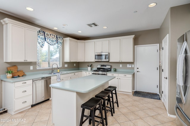 kitchen with appliances with stainless steel finishes, sink, a kitchen island, and white cabinets