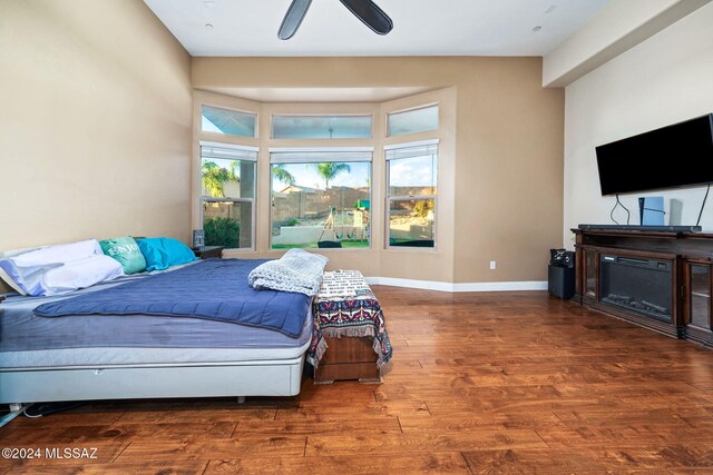 bedroom with dark hardwood / wood-style flooring, multiple windows, and ceiling fan