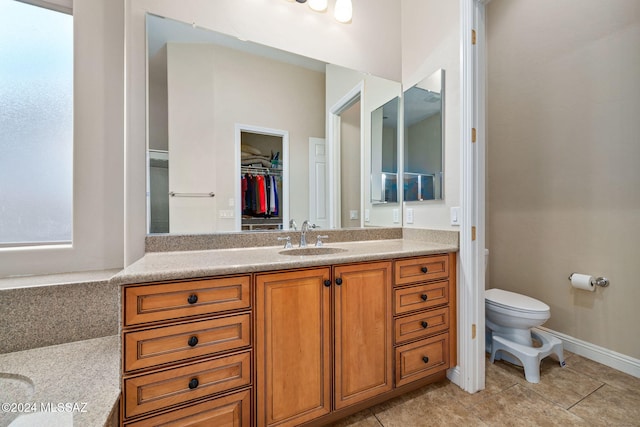 1220 W Calabria Ct, Tucson, AZ 85755 - bathroom featuring vanity, toilet, tile patterned flooring, a walk in closet, and baseboards