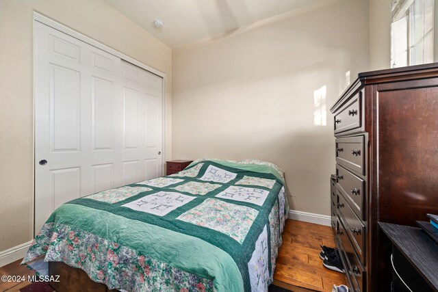 bedroom with dark hardwood / wood-style flooring and a closet