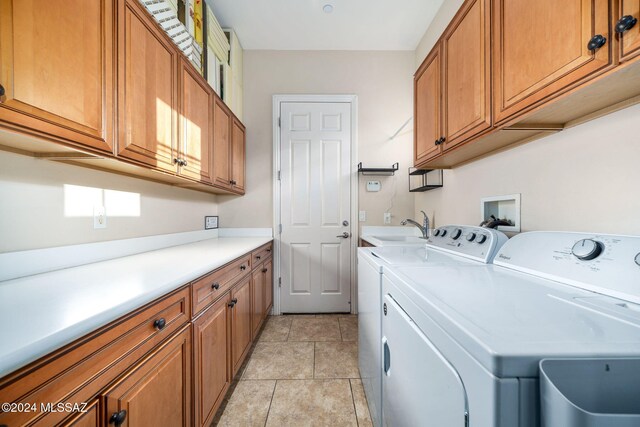 clothes washing area featuring sink, cabinets, washing machine and clothes dryer, and light tile patterned floors