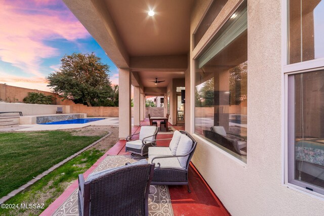 patio terrace at dusk with a fenced in pool, outdoor lounge area, and a lawn