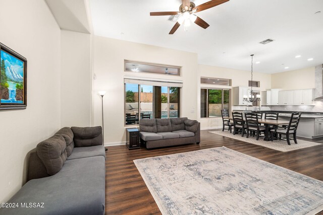 living room with dark wood-type flooring and ceiling fan with notable chandelier