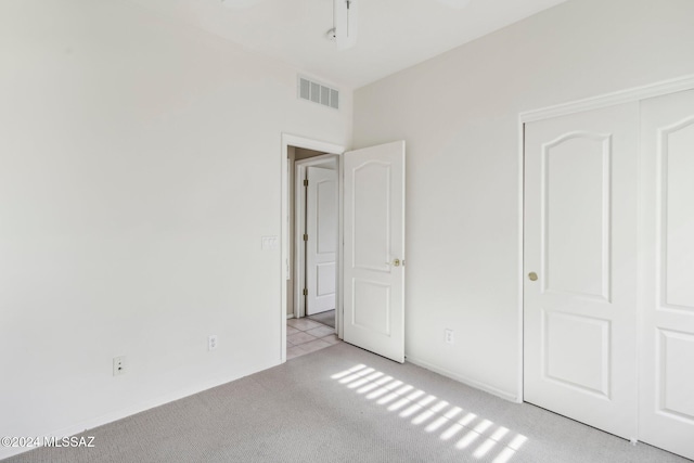 unfurnished bedroom featuring light colored carpet and a closet