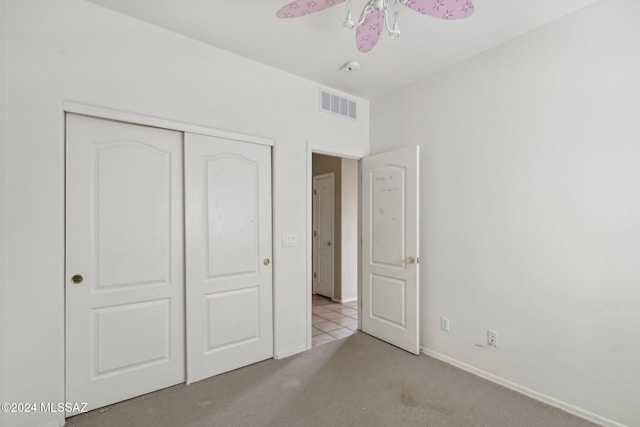 unfurnished bedroom featuring light carpet, a closet, and ceiling fan