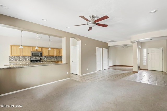 unfurnished living room with ceiling fan, sink, and light carpet