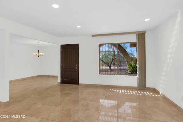 spare room with a chandelier and light tile patterned flooring