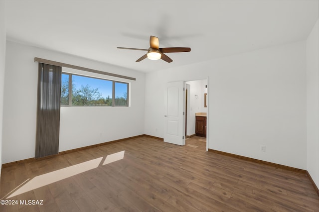 unfurnished bedroom featuring dark hardwood / wood-style flooring, ceiling fan, and connected bathroom