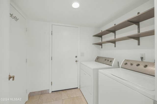 clothes washing area featuring light tile patterned floors and washer and dryer