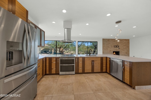 kitchen with sink, stainless steel appliances, range hood, kitchen peninsula, and a fireplace