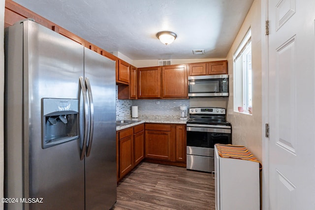 kitchen with light stone countertops, dark hardwood / wood-style floors, tasteful backsplash, lofted ceiling, and appliances with stainless steel finishes