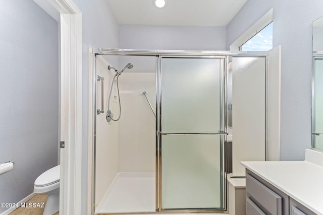 bathroom featuring vanity, a shower with shower door, and toilet