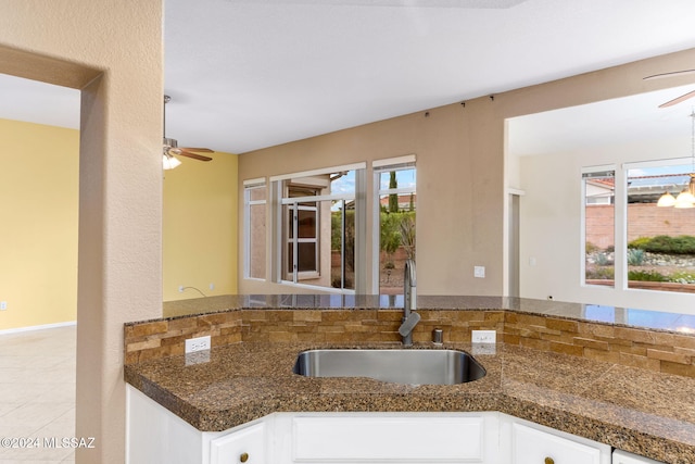 kitchen with white cabinets, a notable chandelier, dark stone counters, and sink