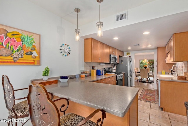 kitchen featuring appliances with stainless steel finishes, sink, backsplash, kitchen peninsula, and hanging light fixtures