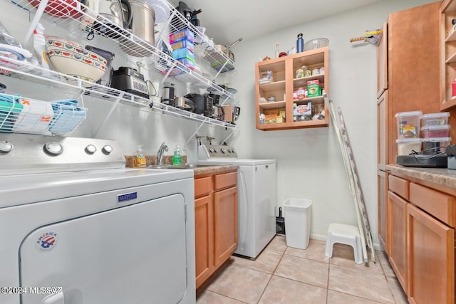 laundry area with sink, washing machine and dryer, cabinets, and light tile patterned floors