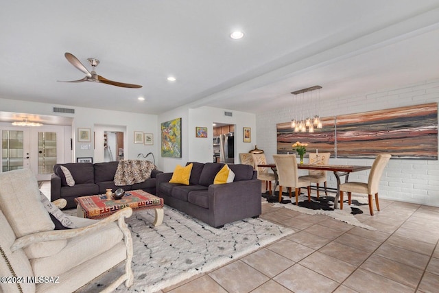 tiled living room with brick wall and ceiling fan with notable chandelier