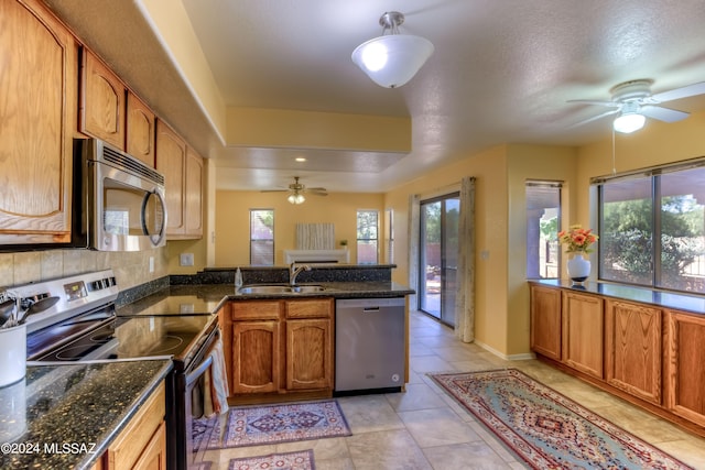 kitchen featuring sink, appliances with stainless steel finishes, a textured ceiling, and dark stone counters