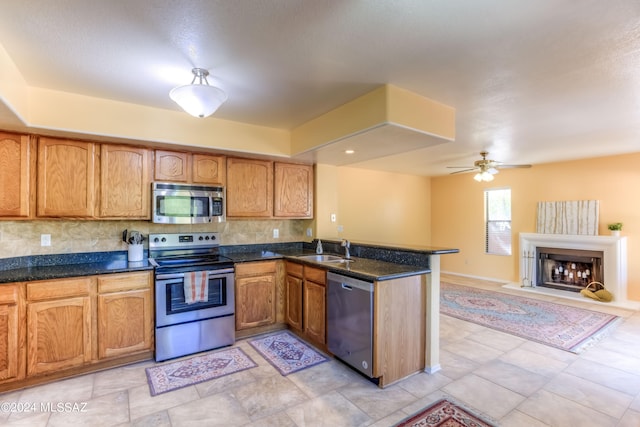 kitchen with backsplash, stainless steel appliances, sink, and kitchen peninsula