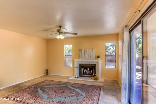 unfurnished living room with ceiling fan, a textured ceiling, and plenty of natural light