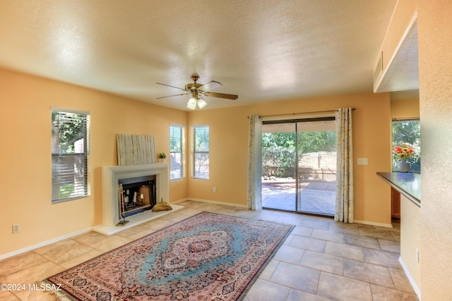 living room featuring light tile patterned floors, a textured ceiling, a healthy amount of sunlight, and ceiling fan