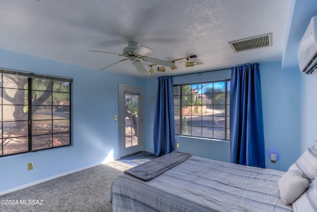 10081 N Pitchingwedge Ln, Tucson, AZ 85737 - carpeted bedroom featuring multiple windows, access to outside, a textured ceiling, a wall mounted air conditioner, and baseboards