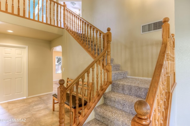 stairs featuring tile patterned floors and a high ceiling