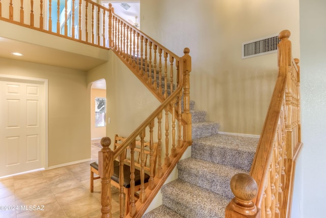 10081 N Pitchingwedge Ln, Tucson, AZ 85737 - staircase with arched walkways, tile patterned flooring, a high ceiling, and baseboards