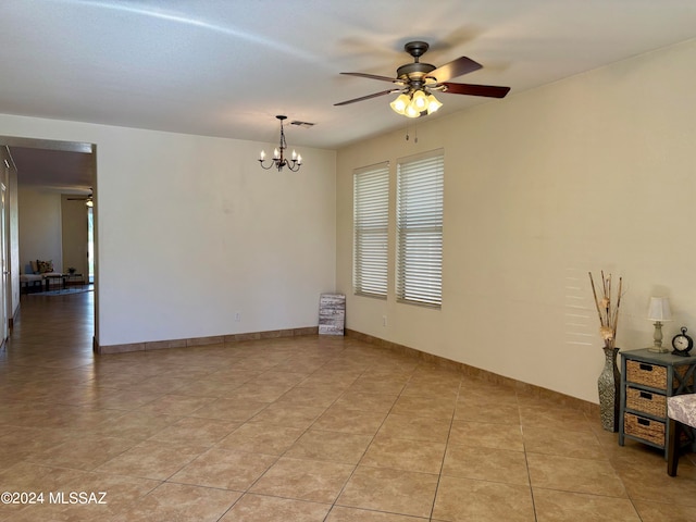 unfurnished room featuring light tile patterned floors and ceiling fan with notable chandelier