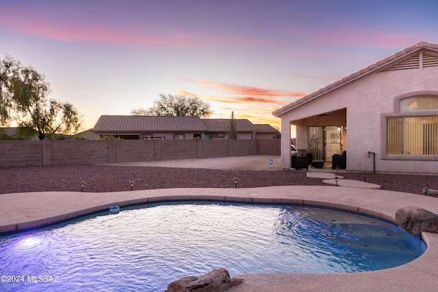 pool at dusk featuring a patio area