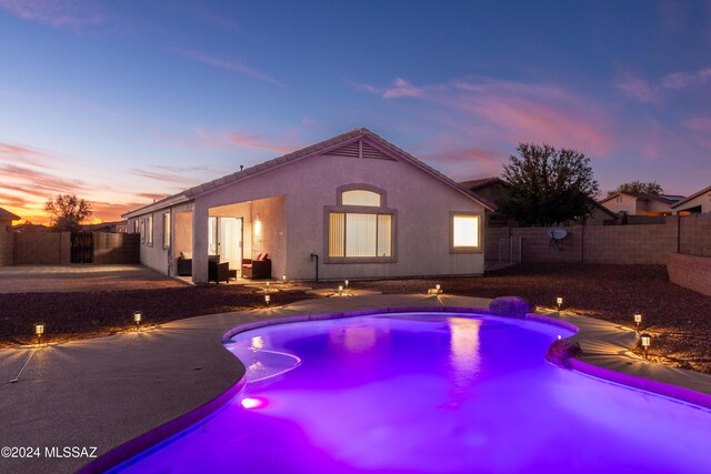 pool at dusk with a patio area