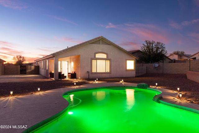 pool at dusk featuring a patio area