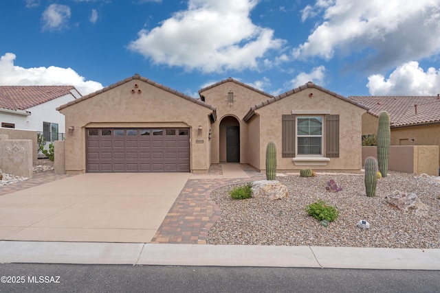 mediterranean / spanish home with an attached garage, driveway, stucco siding, a tiled roof, and fence