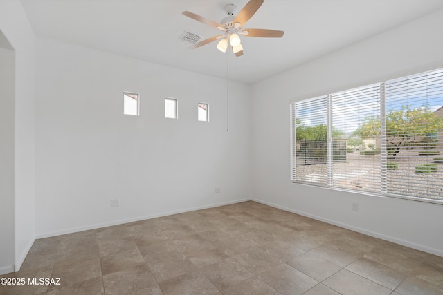 empty room with plenty of natural light, ceiling fan, and baseboards