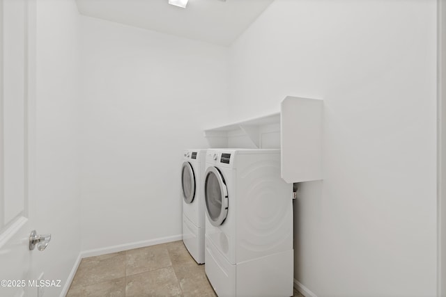 laundry room featuring washing machine and clothes dryer, baseboards, and light stone finish flooring