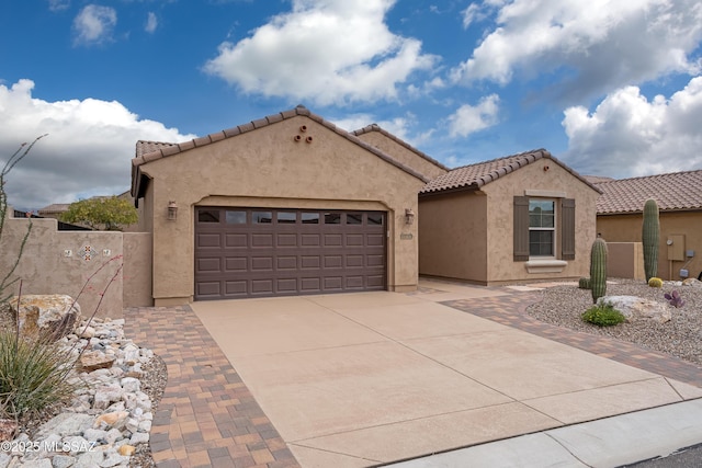 view of front of home with concrete driveway, a garage, stucco siding, and a tile roof