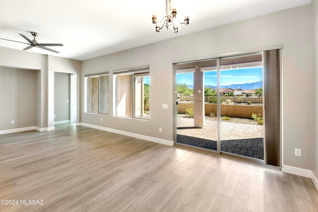 unfurnished room with a mountain view, light hardwood / wood-style flooring, and ceiling fan with notable chandelier