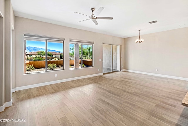 spare room featuring light hardwood / wood-style flooring, a mountain view, and ceiling fan with notable chandelier