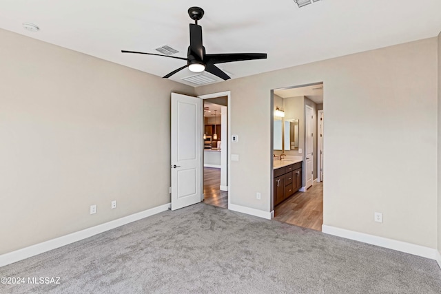 unfurnished bedroom with light carpet, ensuite bath, sink, and ceiling fan