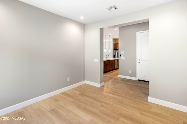 spare room featuring sink and light hardwood / wood-style flooring