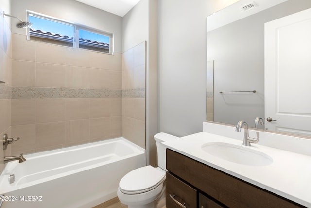 full bathroom featuring vanity, tiled shower / bath, and toilet