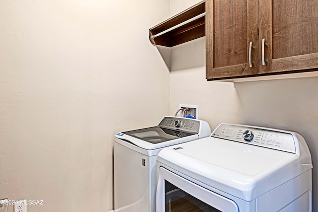 laundry room with washing machine and dryer and cabinets