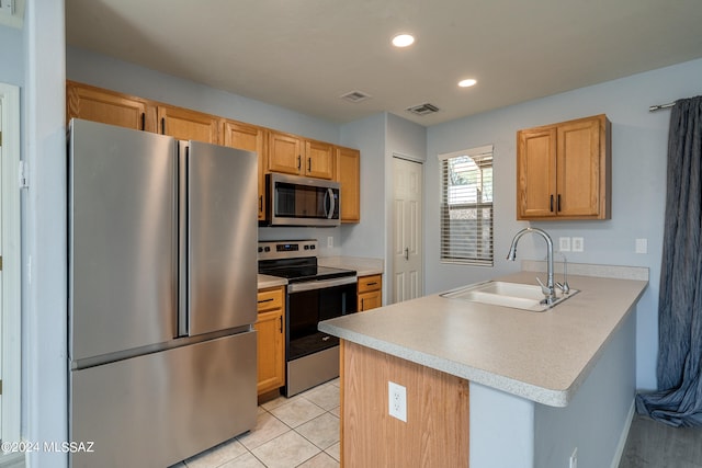 kitchen featuring stainless steel appliances, light brown cabinetry, sink, and kitchen peninsula